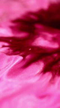 Dikey video. Mürekkep döküldü. Islak sim akışı. Odaklanmamış morumsu pembe renk parıldayan mermer desen boya emülsiyonu soyut sanat arkaplanı yayıyor.