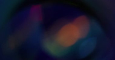 Işık tayfı. Bulanık ışın. Odaksız mavi turuncu çok renkli gökkuşağı kıvılcımlı mercek koyu siyah arka planda yüzüyor..