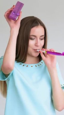 Dikey video. Parti duyguları. Özel bir gün. Mavi elbiseli mutlu bir kadının portresi. Tek başına mücevher kutusuyla dans ediyor. Gülümsüyor..
