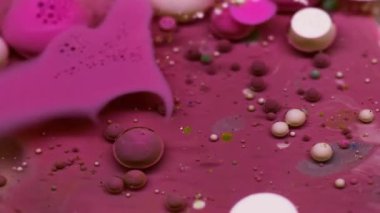 Mürekkep akışı. Kabarcık emülsiyonu. Canlı pembe beyaz su karışımı yüzen renkli damlalar patlama dokusu. Dalgalar soyut arkaplanı doldurur.