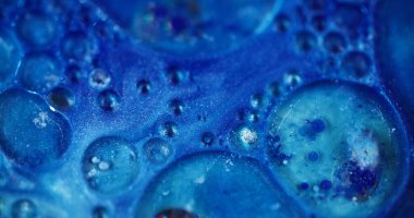 Parlak kabarcıklar. Odaklanmamış parlaklık rengi. Soyut, bulanık, aydınlık, modern arka planda mavi, pırıl pırıl parlayan, parlak sıvı hareket..