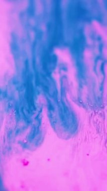 Dikey video. Su damlası. Sihirli sıvı karışımı. Odaklanmamış açık neon mavisi pembe mor su altı mürekkep akışı sıvı karışımı soyut sanat arkaplanı.