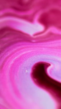 Dikey video. Parıltılı boya karışımı. Parlak sıvı dökülmüş. Odaklanmamış morumsu pembe beyaz renk parıldayan parçacıklar doku mürekkep karışımı soyut sanat arkaplanı.