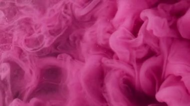 Mürekkep dumanı. Pembe duman. Parlak bulut tüm yüzeye yayılır. Suyun soyut arkaplanındaki karmaşık kıvrımlı parçacıklarla dekoratif olarak sislenmiş boya.