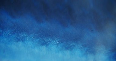 Mavi dalga. Odaklanamayan köpüklü su. Bulanık bokeh ışığı soyut modern arka planda yanıp sönen yapışkan sıvı hareket.