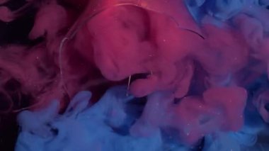 Renkli duman. Boya bulutu. Parıldayan mavi dalga pembe mürekkep siyah arka planda patlıyor. Kırık ampul parçalarıyla soyut dökülme boyası.