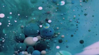 Kabarcık emülsiyonu. Pigment dökülmüş. Yuvarlak turkuaz mavi parçacıklar boya dökülmesini şeffaf bir sıvıda karıştırıyor. Petrol sanatı suyu soyut arkaplan.