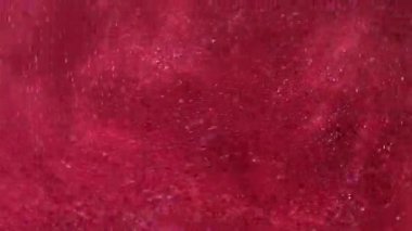 Parıltılı bir dönüş. Parlak sıvı. Odaklanmamış pembe renkli parlak toz parçacıkları su mürekkebi emülsiyon girdaplı soyut sanat arka planında titreşir.