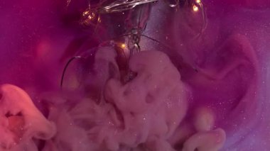 Pembe sıvı. Boya patladı. Çok renkli duman kıvrımları garip bir şekilde ışıl ışıl sanat sıvısı arka planlarını karıştırıyor. Duvak dumanı patlamış ampul..