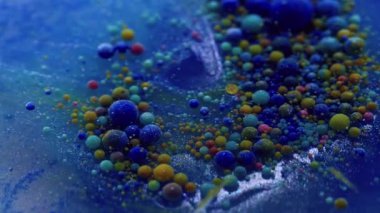 Sıvı boya. Su damlasını boya. Mavi suda yüzen odaksız renkli kabarcıklar. Patlayan jel dokusu serumu soyut sanat arkaplanı.