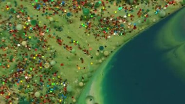 Boya akışı. Sanat sıvısı. Yeşil sarı sıvı sızıntı... yağ lekesi... pudra yüzeyi. Renk parçacıklarını soyut bulanık arkaplanla karıştır.