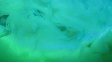 Mürekkep buharı. Puf boyası. Işıldayan suda yeşil mavi turkuaz girdap bulutu akıyor. Gizemli odaksız peçe sanatı soyut neon akış arkaplanı.
