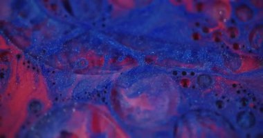 Parlayan sıvı. Odaklanamayan kozmetik titreşimler. Mavi kırmızı boya şeffaf kabarcıklar bulanık bokeh ışık arka planında hareket ediyor.