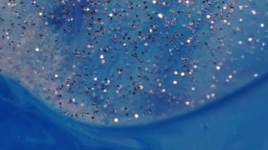 Parıldayan sıvı. Boya karışımı. Parıldayan metal parçacıkları mavi sanatsal suda yüzüyor. Soyut odaklanmış nem arkaplanı.