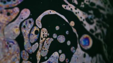 Soyut psikedelik. Sabun gökkuşağı. Odaklanmamış mor yeşil sıvı yağ eğrisi koyu siyah bulanık ışık sanat arka planında akrilik kaygan.