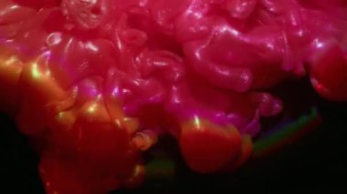 Parlayan toz. Boya patlaması. Parlak dumanlı pembe turuncu parlak dalga siyah arka planda. Sanat sıvısı tozu soyut bulanık doku.