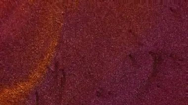 Parıltılı boya. Barut akışı. Işıldayan mürekkep sanatı sıvısı renk karışımı soyut arkaplan. Mor kırmızı turuncu kum hipnotik bulanık yüzey.