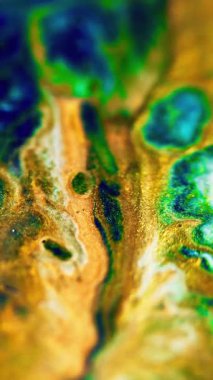 Dikey video. Parlak mürekkep karışımı. Islak sim akışı. Odaklanmamış altın rengi cyan mavisi metalik ışıldayan parçacıklar mermer desen boya soyut sanat arkaplanı sıçrıyor.