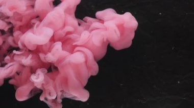Boya damlası. Atmosferik duman. Odaklanamayan pembe renkli su akışı kimyasal sıçrama fantazisi soyut sanat esmer arka planda büyüyor..