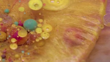 Parıltı akıyor. Kabarcık patladı. Renkli pırıl pırıl altın sıvısı ve yuvarlak jel dökülmüş. Sarı pembe leke parlak su soyut arkaplan.