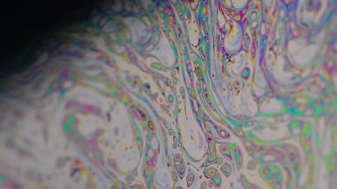 Boya karışımı. Benzin var. Odaklanamayan mor yeşil sıvı yağ eğrisi koyu siyah, bulanık ışık, soyut sanat arka planında akrilik kaygan.