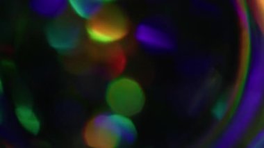 Bulanık ışınlar. Parıldayan ışık. Odaklanamayan sızıntı, çok renkli yeşil gökkuşağı ışıltılı lens parlamaları soyut sanat koyu siyah bokeh arka plan.