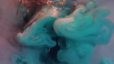 Sıvı patlaması. Köpüklü sıvı. Bulutlu turkuaz mürekkep boyası mistik bir şekilde süt gibi parlayan su arka planına yayılır. Renkli sanat dalgaları kırık ampulü aydınlattı.