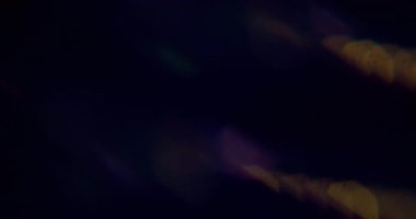Işık parlıyor. Bulanık işaret fişeği. Odaklanmamış mavi mor renkli lens soyut koyu siyah arkaplan üzerinde parıltı deseni.
