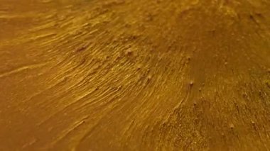 Parıltı yayılıyor. Lüks boya. Altın akımlarda değerli sıvı toz, sanat yüzey parçacıkları. Soyut pembe fantezi ışınları siyah arkaplanı çözdü.