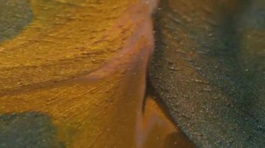 Shimmer döküldü. Lüks boya. Değerli sıvı toz altın sarısı turuncu akımlar sanat yüzey parçacıkları döküyor. Soyut gri karışım ıslak odaklanmış arkaplan.