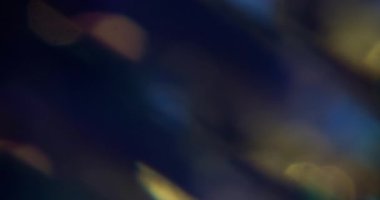 Parlak lens. Bulanık kıvılcım dokusu. Odaklanamayan sarı mor çok renkli sihirli ışık soyut sanatın koyu siyah arka planında yanıp sönüyor..
