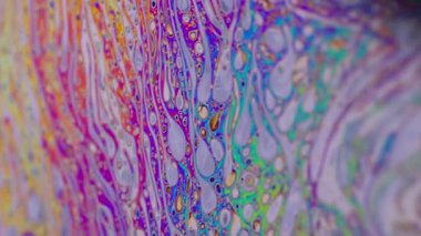 Parlak kabarcık yapısı. Yağ sıvısı. Odaklanmamış mor renkli yeşil boya eğrisi koyu siyah, bulanık ışık, soyut sanat arka planında akrilik kaygan.