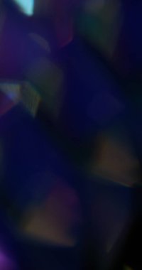 Optik ışıltı. Bulanık spektrumlu işaret fişeği. Soyut koyu siyah arkaplan üzerinde sönük mavi sarı renkli lens kıvılcım saçar.