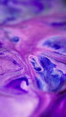 Dikey video. Parlak sıvı sıçraması. Boya karışımı. Odaklanmamış mor renk parlak parçacıklar parlayan doku mürekkep dalgası soyut sanat arkaplanı.