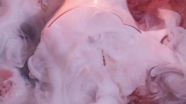 Işıldayan boya. Sanat bulanıklığı. Pembe mat kırmızı parıltılı duvak soyut karışımı siyah arka plan. Kırık ampul parçaları. Renkli suyla aydınlatılmış çelenk..