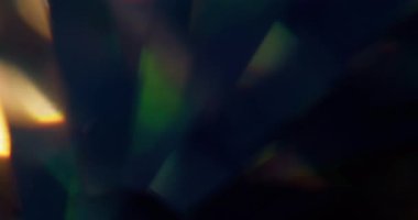 Holografik ışık. Bulanık mercek titreşiyor. Odaklanmamış mavi yeşil renkli gökkuşağı dokusu soyut koyu siyah arkaplanda parıldıyor.