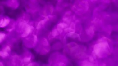 İşaret fişeği. Mor konfeti. Işıltılı noktaların pürüzsüz geçiş noktalarıyla parıldayan yuvarlak noktalar. Mor renkli yanardöner parıltı..