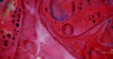 Parlayan baloncuk. Odaklanamayan parlayan sıvı. Yanıp sönen kırmızı beyaz parlak renkli su bulanık bokeh ışıklı arka planda hareket ediyor..