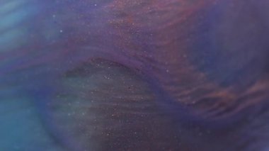 Köpüklü sıvı. Dalgalı akış. Yüzeyinde dalgalanmalar olan parıldayan mavi bir akıntı. Parlak bulanık sıvı boya ve karışık boya parçacıkları etkisi.