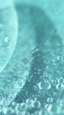 Dikey video. Yağlı su karışımı. Köpük sıvısı. Odaklanmamış açık mavi renk sıvısı girdap ıslak parlaklık dokusu sarmal emülsiyon soyut sanat arka planı.