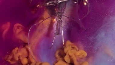 Işıl ışıl. Parlak duman. Pembe parıldayan sanat sıvısını karıştıran turuncu duman spreyi. Açık renk çelenk kırık ampul soyut su arkaplanı.