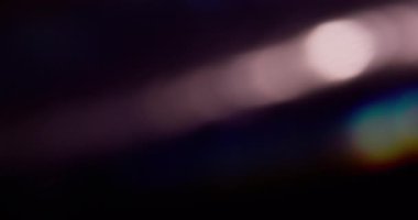 Yansıma bokeh. Bulanık parıltı. Siyah sanat arka planında sönük mavi yeşil çok renkli gökkuşağı tayfı yanıp sönüyor..