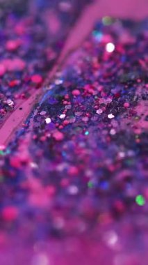 Dikey video. Sıvı ışıltılı doku. Parıltılı boya döküldü. Mor, pembe, parlak, pullu, pullu parçacıklar. Sıvı, emülsiyon, mürekkep damlaları. Bokeh ışıklarıyla soyut sanat arka planı..