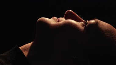 Dikey video. Huzurlu bir yüz. İlham verici bir siluet. İçsel sükunet. Siyah üzerine izole bir şekilde gülümseyen mutlu kadın profili..