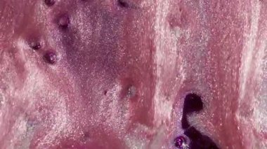 Parıldayan sanat. Parlak lekeler. Soyut arkaplanda hareket eden suda pembemsi pembe pigment sıvı yağ damlası boya akışı.