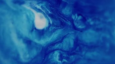 Yağ akışı. Bulanık parıltı dokusu. Parıldayan mavi beyaz parçacıklar boya damlası dalgası soyut sanat arka planına düşüyor.