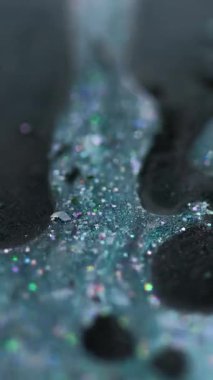 Dikey video. Sıvı sim dökülmüş. Mürekkep sıvısı. Bulanık deniz mavisi siyah holografik pullu parçacıklar boya damlaları emülsiyon jel damlaları hareketli soyut sanat arka planı Bokeh ışıkları.