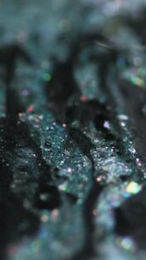 Dikey video. Parıldayan sıvı dökülmüş. Işıldayan boya. Bulanık deniz mavisi siyah holografik parçacıklar yağ emülsiyon damla hareket soyut sanat arka planı Bokeh ışıkları ile.