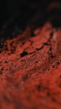Dikey video. Boya akışı. Islak sim dokusu. Soyut sanat arka planında çözünmüş kırmızı siyah renkli, parıldayan sıvı mürekkep karışımı dalga hareketi.