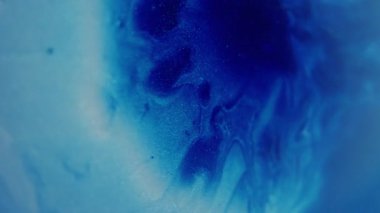 Islak sim dokusu. Bulanık boya akışı. Mavi beyaz çok renkli sıvı ışıldayan sıvı köpüklü su soyut bokeh ışık arka planında hareket ediyor.